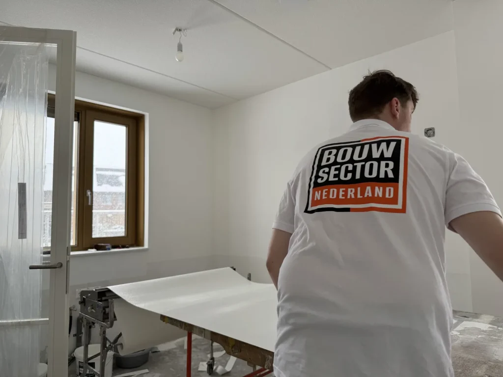Behanger van Bouwsector Nederland trekt een baan vlies van de plaktafel in een slaapkamer